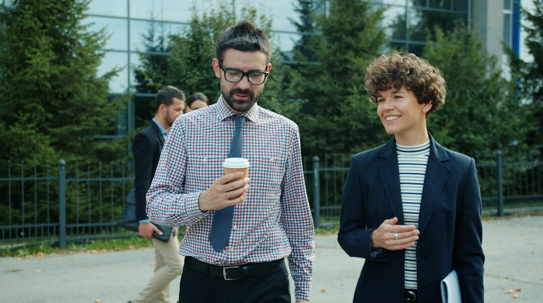 Small group of colleagues walking and talking in a bright office hallway